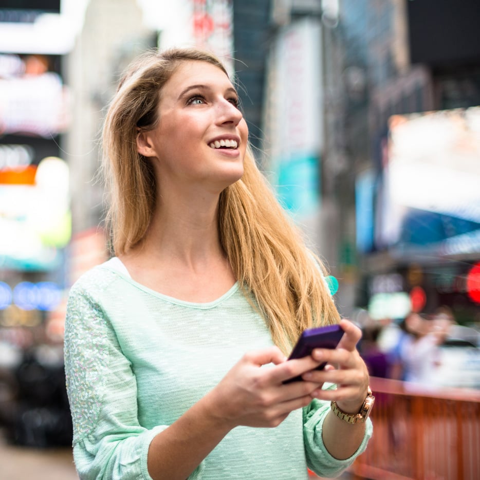 Woman holding mobile phone looking up